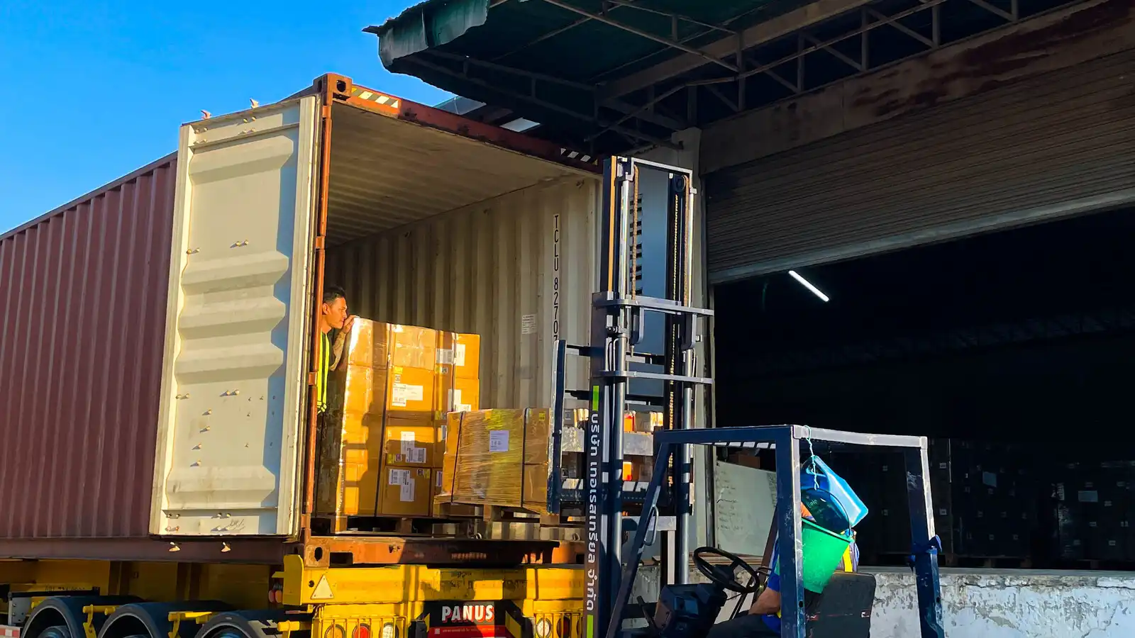 Forklift loading cartons into a shipping container at a warehouse
