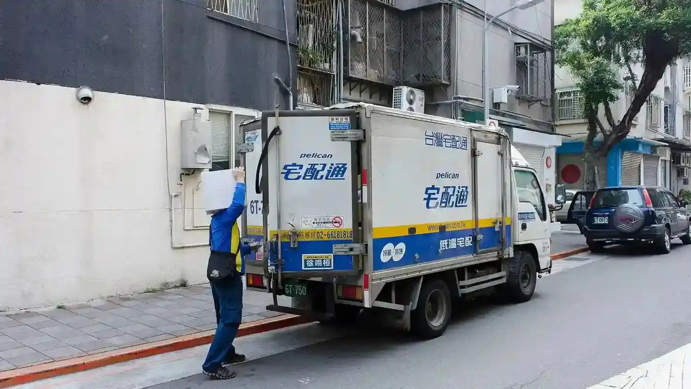 Delivery driver unloading cartons from a truck at the curb