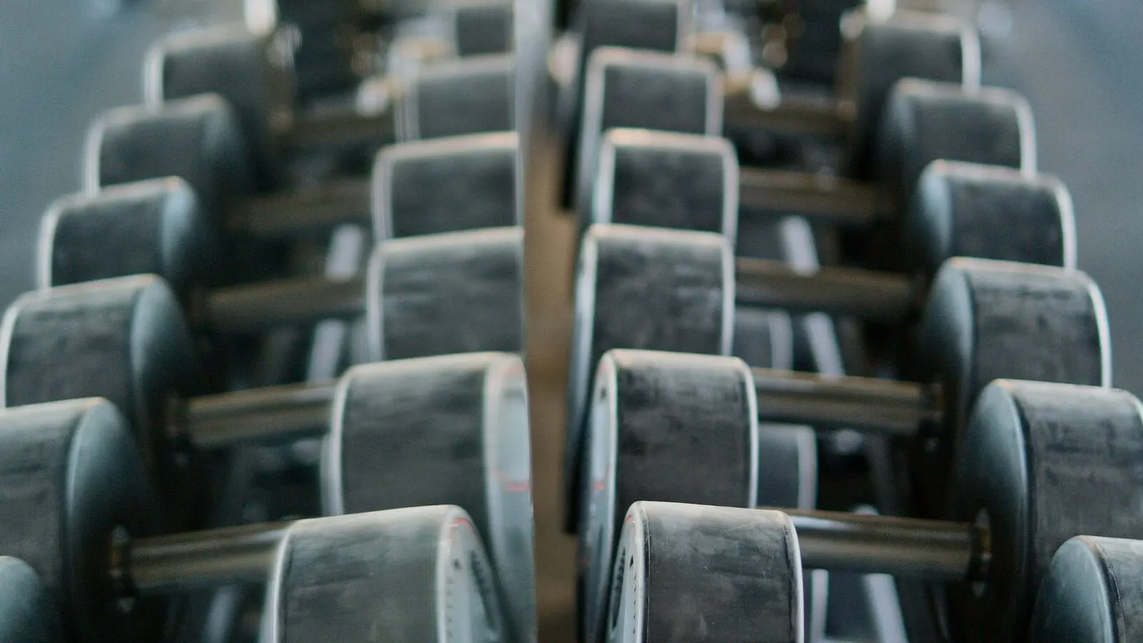 Dumbbell rack reflected in a full-height gym wall mirror