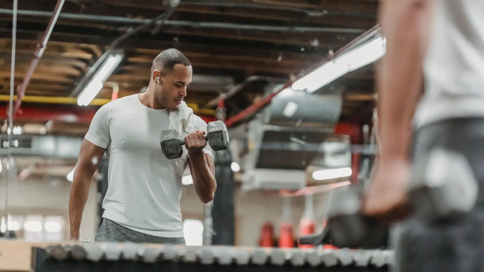 Member training with dumbbells in a mirrored gym area
