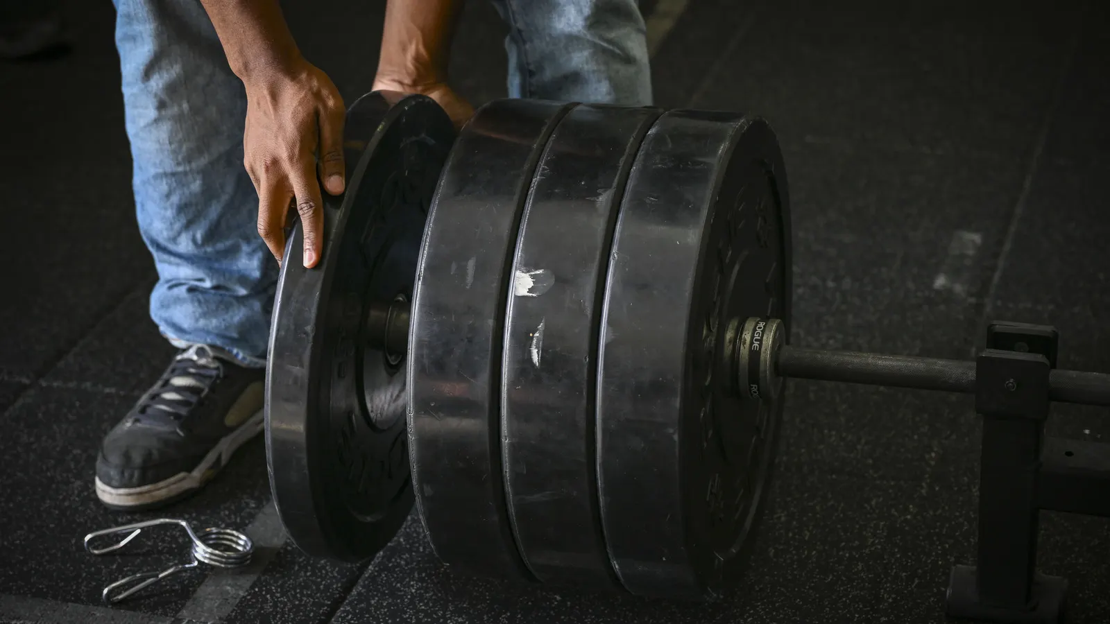 Weight plates being loaded onto a barbell during a powerlifting competition