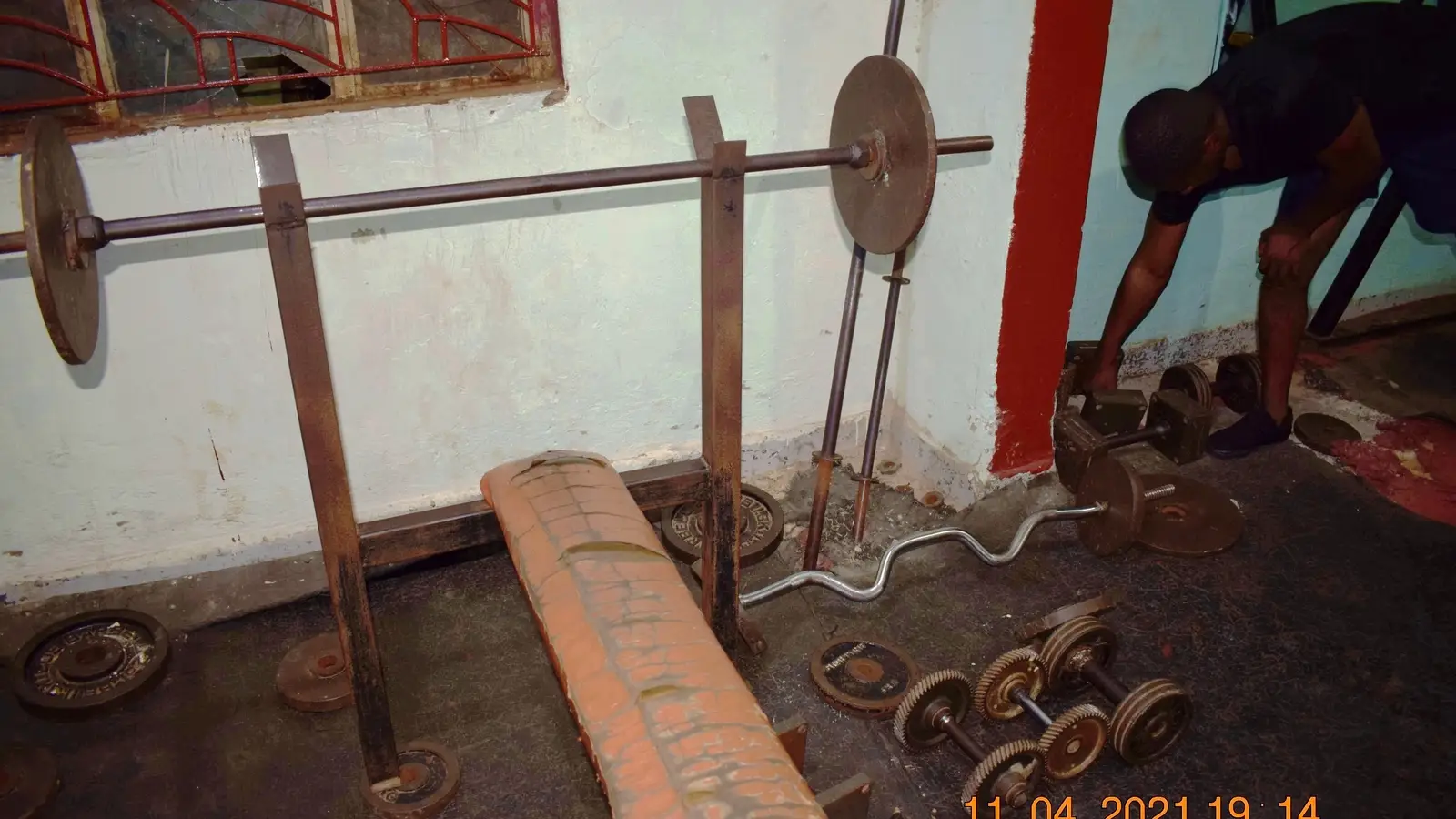 Barbells and dumbbells stored in a commercial gym weight room, where specialty bars need their own rack space